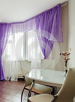 Modern cozy home interior dining room with white table, chairs, violet curtains, dry flowers vase