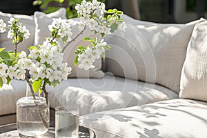 Modern cozy living room interior with stylish sofa, coffee table, and blooming branches in vase