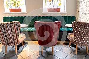 A modern cozy restaurant with colorful upholstered chairs and comfortable sofas. Unusual cafe design with rough concrete walls and