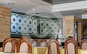 A modern cozy restaurant with a long table for a large number of people. Wooden furniture in retro style. There are napkins and