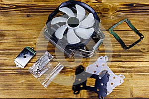 Modern CPU cooler with installation kit on wooden desk. Top view