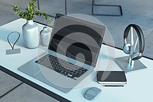 Modern creative designer desktop with laptop and reflections, decorative vase and supplies.