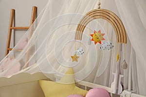 Modern crib with baby mobile in children`s room. Interior design