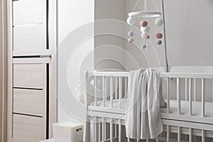 Modern crib with baby mobile in children`s room. Interior design