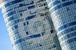 Modern curved glass skyscraper with reflective windows against a clear blue sky photo