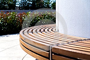 Modern curved shaped brown wooden outdoor design bench in green zone