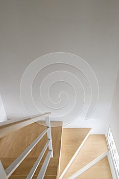 The modern curved wooden staircase with the white metal handrail