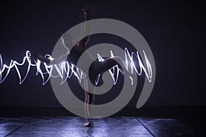 Modern Dance performer dancing with a neon blue light while making gracious moves and spectacular body art expressions