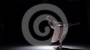Modern dancer girl in white continues dancing contemporary, whirls on black, shadow, slow motion