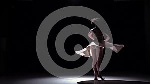 Modern dancer girl in white dress dancing contemporary, whirls on black, shadow, slow motion