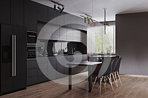 Modern dark kitchen and dinning room interior with furniture and kitchenware, grey, black and dark wood kitchen interior