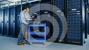 In the Modern Data Center: Engineer and IT Specialist Work with Server Racks, on a Pushcart Equipm