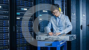 In the Modern Data Center: IT Engineer Wearing Protective Muffs Installs New Hardware for Server R