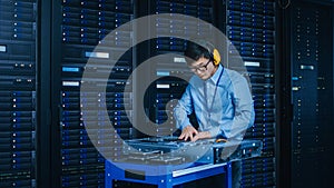 In the Modern Data Center: IT Technician Wearing Protective Headphones Working with Server Racks,