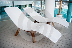 Modern deck chairs at luxury hotel. Private swimming pool for relaxation, with beautiful interior.