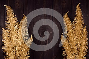 Modern decoration for celebration - golden glimmer branches on brown wood plank, frame, top view.