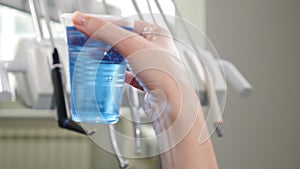 Modern dental clinic. Medical equipment in disfocus with plastic cup with blue aseptic liquid in front. 4k