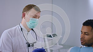 Modern dental clinic patient man sitting on dentist chair and speaks with the doctor the dentist showing the process of