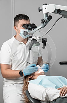 A modern dentist who uses advanced technologies in his practice treats the patient under a microscope to ensure the
