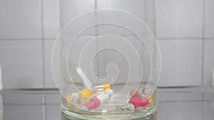Modern dentistry concept. Empty dental Implant containers falling down in slow motion within glass bowl Symbolizing much