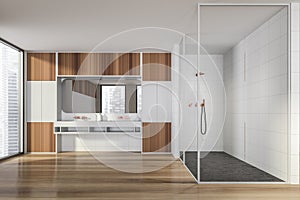 Modern design bathroom interior with glass shower cabin, double sink countertop, bronze faucets. Panoramic window with skyscrapers