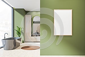 Modern design of bathroom interior with grey bathtub, sink, mirror, beige ceramic tile, panoramic window. White framed poster on
