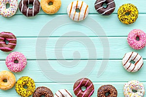 Modern design with bright donuts frame on mint green wooden background top view mock up