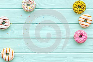 Modern design with bright donuts on mint green wooden background top view mock up