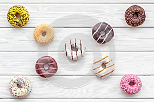 Modern design with bright donuts on white wooden background top view