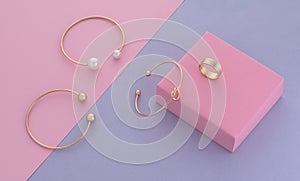 Modern design golden jewelries on pink box on purple background