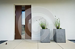 Two cubic concrete flower pots at front door of a house photo