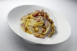Modern design soup plate with spaghetti carbonara on table with tablecloth