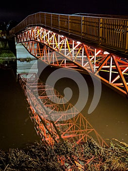 A modern design steel bridge over a river at night with a water reflection