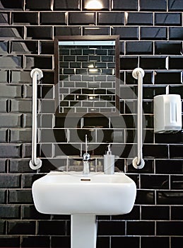 Modern design of toilet closet room with black glossy tiles.