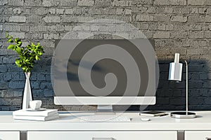 Modern designer desktop with empty computer monitor, lamp, supplies and other items. Black brick wall background. Mock up, 3D
