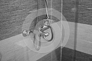 Modern designer tap and shower in bathroom. Closeup of chrome shower, faucet, in the bathroom covered decorative ceramic