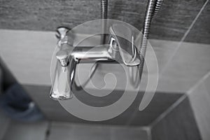 Modern designer tap and shower in bathroom. Closeup of chrome shower, faucet, in the bathroom covered decorative ceramic