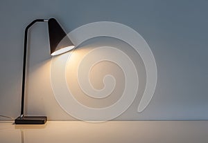 The modern desk lamp illuminate on the wall background.