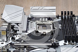 A modern desktop motherboard in black color with a visible socket 1200 for the CPU, memory slots DDR4 and heat sinks.