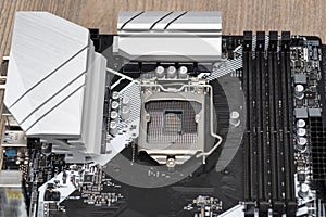 A modern desktop motherboard in black color with a visible socket 1200 for the CPU, memory slots DDR4 and heat sinks.