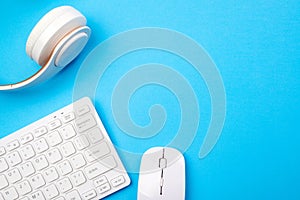 Modern devices for your leisure at home. Work from home. White keyboard, mouse and headphones on blue background, top view