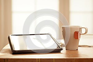 Modern Digital Devices on Wooden Table, Blurred windows background, Digital Tablet, Tea and Newspaper