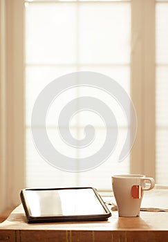 Modern Digital Devices on Wooden Table, Blurred windows background, Digital Tablet, Tea and Newspaper