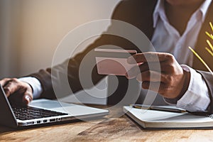 Modern digital financial lifestyles. Businessman holding credit card and doing bank payment via internet by computer