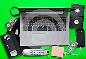 Modern digital gadgets, storage media, devaysy and obsolete analog media devices on a green paper background. Top view. Flat lay