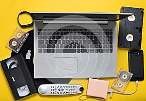 Modern digital gadgets, storage media, devaysy and obsolete analog media devices on a yellow paper background. Top view. Flat lay
