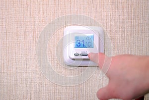 Modern digital programmable thermostat with liquid crystal display and buttons, with white panel on a white background