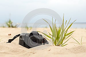 Modern digital SLR camera lying on the sand on the beach