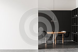 Modern dining room interior with a wooden table, black chairs, and a pendant lamp. Black and white background, minimalist concept