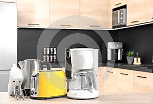 Modern domestic appliances on wooden table in kitchen.